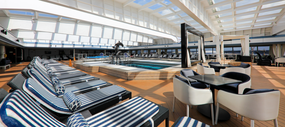 Lido Deck der VASCO DA GAMA mit Pool, zahlreichen Sonnenliegen und Sitzgruppen unter einem großen verglasten Dach.