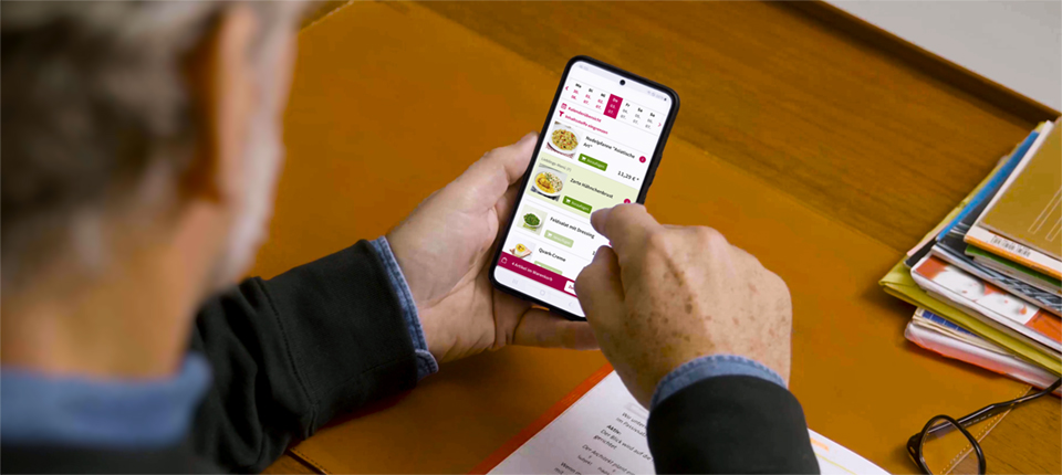 Ein Herr bestellt über eine App auf dem Handy sein Essen auf Rädern.